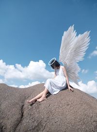 Woman with arms raised against sky