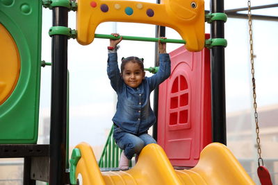 Full length of happy girl on slide at playground
