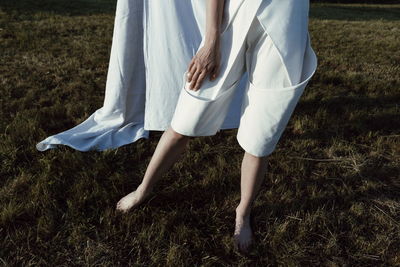 Low section of woman with umbrella on field