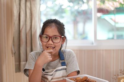 Portrait of smiling girl eating food at home