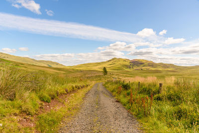 Road amidst field against sky