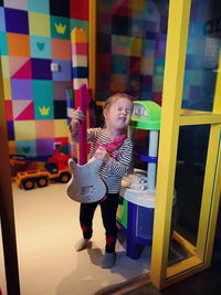 Girl with toy guitar standing at home