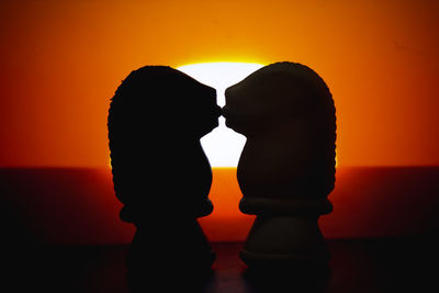 Close-up of silhouette couple standing against orange sunset sky