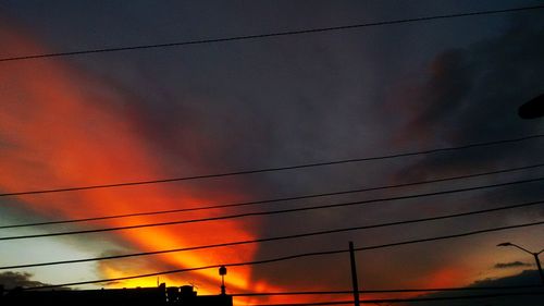 Low angle view of power cables against cloudy sky