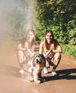 Digital composite image of woman crouching by dog on footpath reflecting in glass