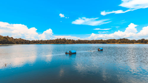 Containers on lake against blue sky