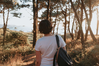 Rear view of woman standing in forest