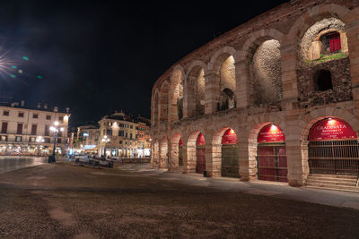 Illuminated road amidst buildings in city at night