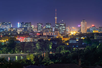 Illuminated buildings in city against sky at night