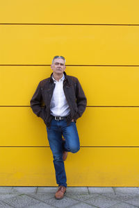 Full length of man standing against yellow wall