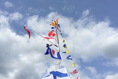 Low angle view of flags against cloudy sky