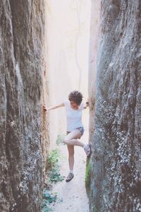 Woman trying to climb wall amidst alley