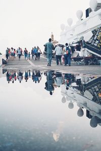 People on airport runway against clear sky