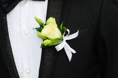 Midsection of bridegroom wearing suit with yellow rose in pocket