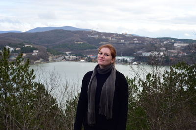 Portrait of smiling young woman standing against sky