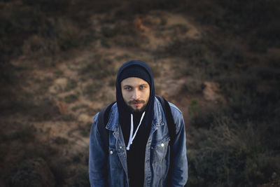 Portrait of man in hooded shirt standing on field