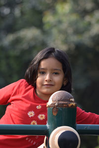 Portrait of young woman sitting against trees