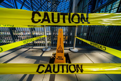 Close-up of warning sign on yellow barricade