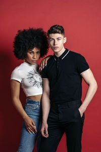 Stylish diverse girlfriend and boyfriend posing in a studio shooting with red background