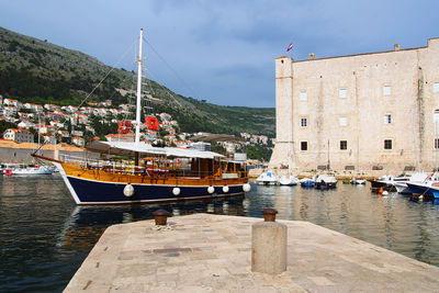 Boats moored at harbor against sky