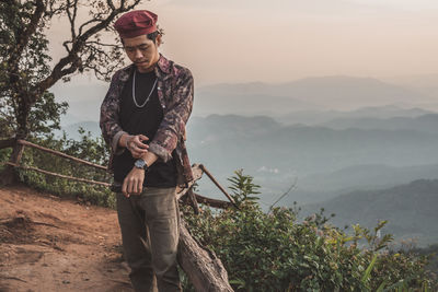 Young man standing on mountain against sky