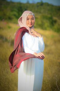 Portrait of bride wearing hijab while standing on field