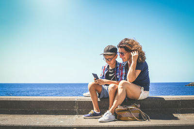 Mother and son using smartphone together. smiling kid and mum doing video call with  mobile phone. 