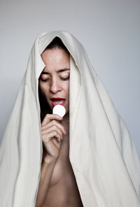 Portrait of beautiful woman lying on bed against white background