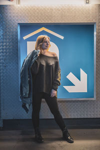 Woman standing against information sign