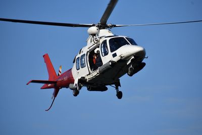 Low angle view of helicopter flying against clear blue sky