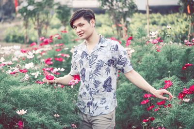 Beautiful young woman standing by flowering plants