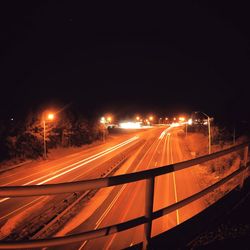 Light trails on road against sky at night