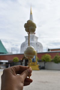 Close-up of hand holding ice cream against sky