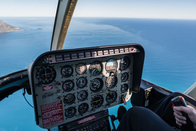Midsection of pilot flying helicopter over sea