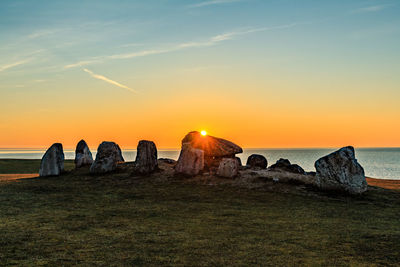Rock on grass field against river