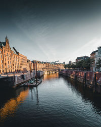 Buildings by river against sky in city