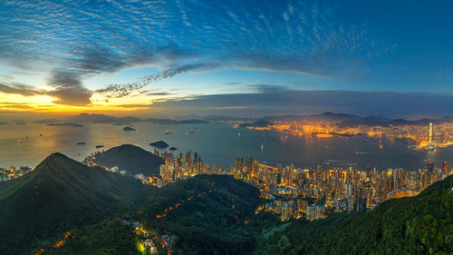 Aerial view of illuminated city against sky at sunset