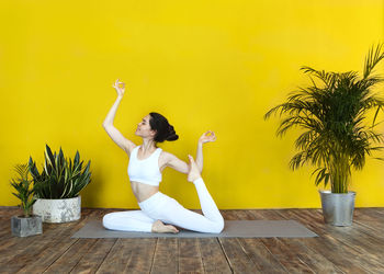 Young woman exercising by potted plants