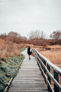 Rear view of man walking on footbridge