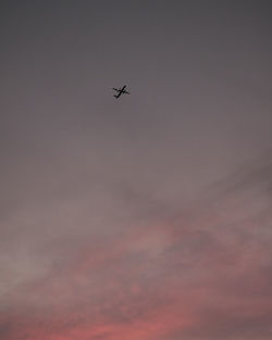 Low angle view of silhouette airplane against sky during sunset