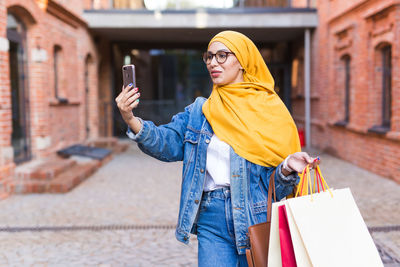 Midsection of woman holding mobile phone in city