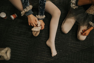 Overhead shot of young girl putting foot in ballet slipper