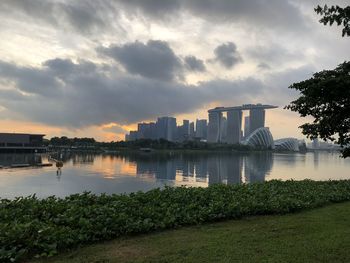 Scenic view of river by buildings against sky during sunset