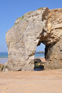 Rock formation on beach against clear sky