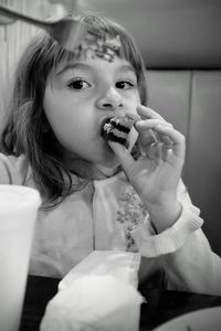 Portrait of cute girl eating cake slice at restaurant