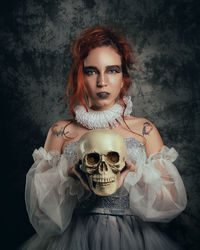 Fine art photography of a woman handling a skull in a dark background