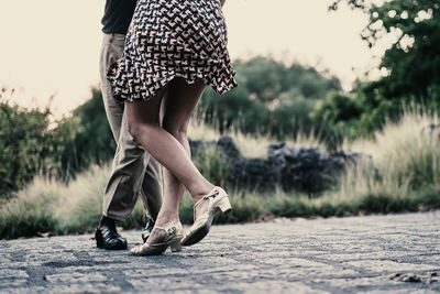 Low section of couple dancing on footpath