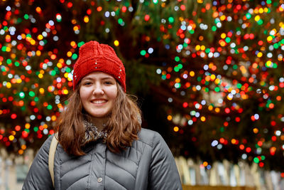 Portrait of smiling girl wearing hat against illuminated lights