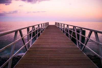 Pier over sea against sky during sunset