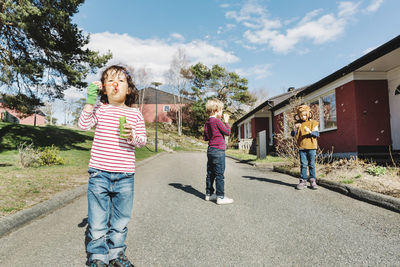 Friends playing with bubble wands on footpath at yard